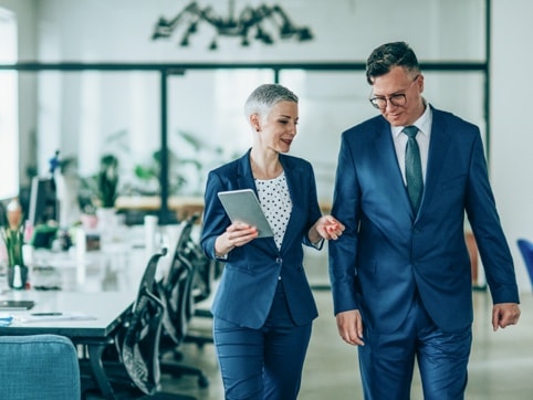 A male and a female in suits talking as they walk
