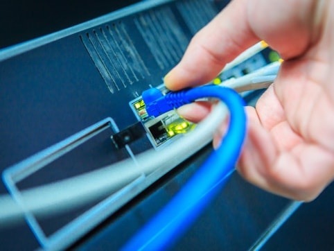 Close up view of someone connecting a cable to a server